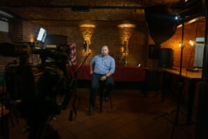 Entrevistado sentado en el set de filmación de DG Video Producción, con luces de estudio y fondo de ladrillo